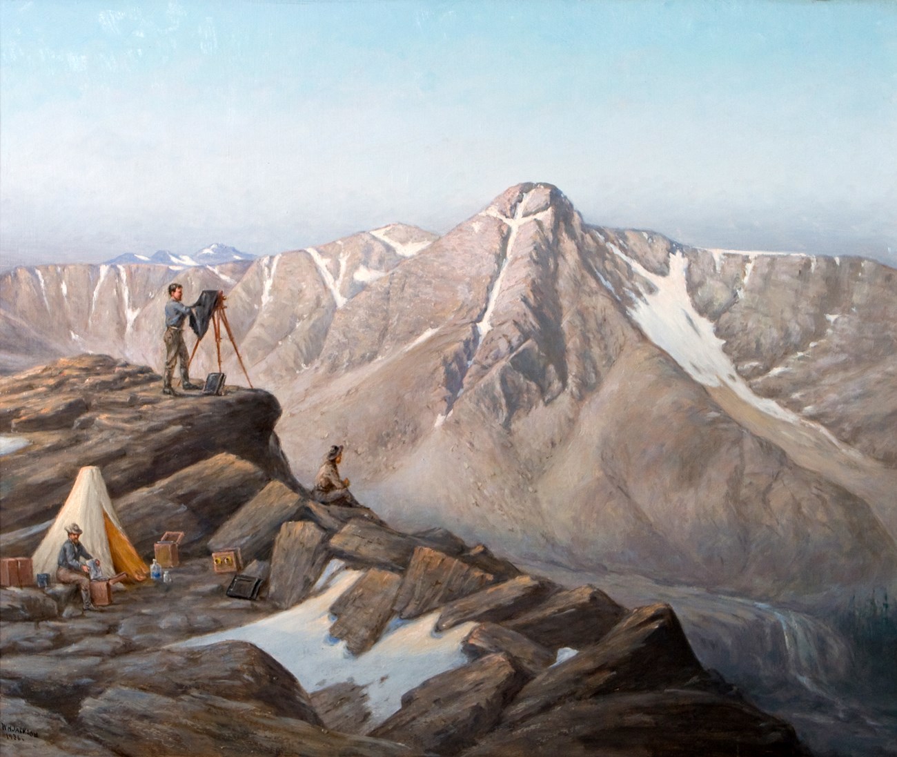 A man has a camera set on a tripod on a high mountain overlook.