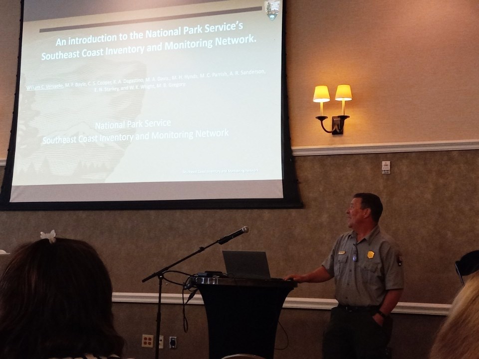 Man in uniform standing next to a screen giving a presentation