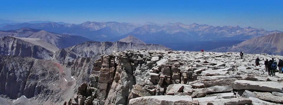 Hikers on the top of a mountain overlooking a mountain range