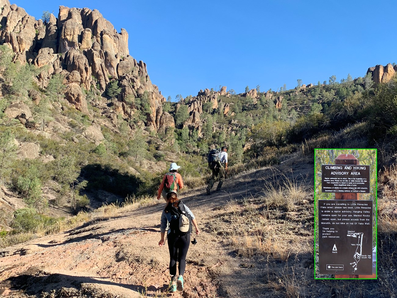 Hiking Condor Gulch Biologist leading two other people and the photographer on a hiking trail through a shrubby landscape towards towering rock formations. Inset: A sign reads "Climbing and Hiking Advisory Area".