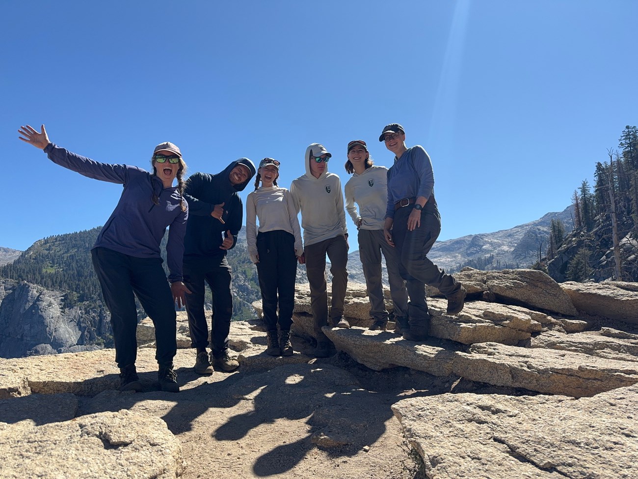 Six crew members stand together on a high mountain ridge.