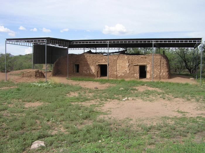 San Cayetano de Calabazas Adobe structure with two doors and one window. It has a corrugated metal preservation structure covering the roof.