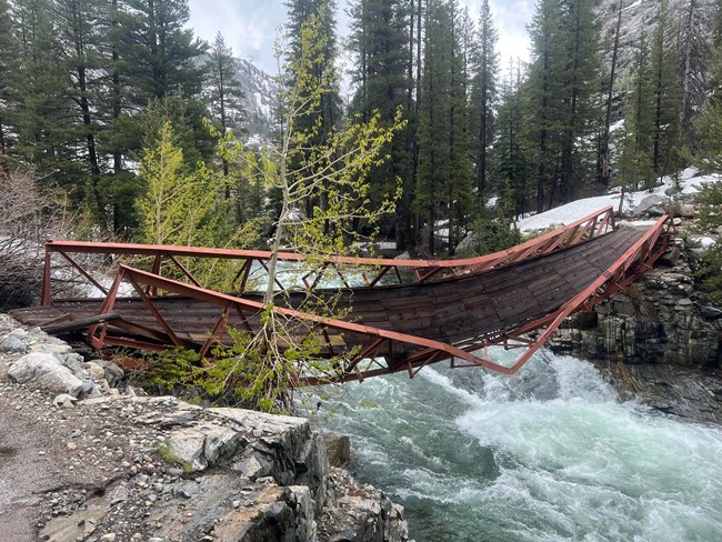San Joaquin Bridge twisted above a roaring creek. San Joaquin Bridge broken and twisted above a raging creek.