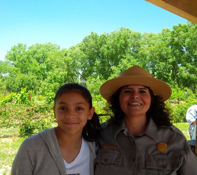 A park ranger and a young girl standing next to each other.