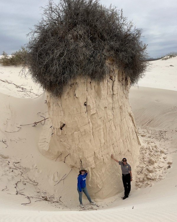 Sarah Melody pedestal Two women, one in SCA uniform and one in NPS uniform, stand in front of a massive, 30-foot tall white sand pedestal.
