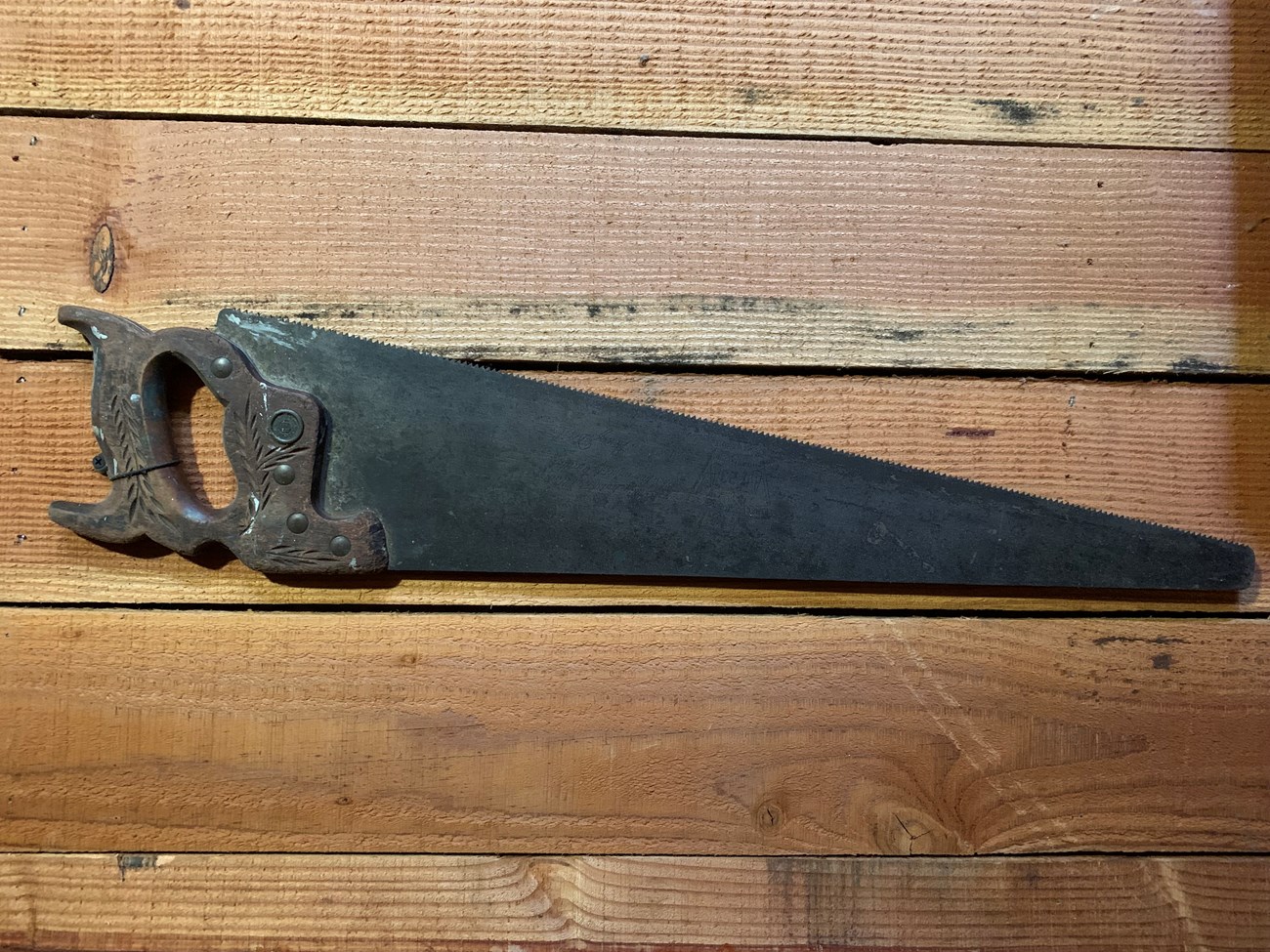 Nick Sacco Metal saw with wooden handle hanging on a wall.
