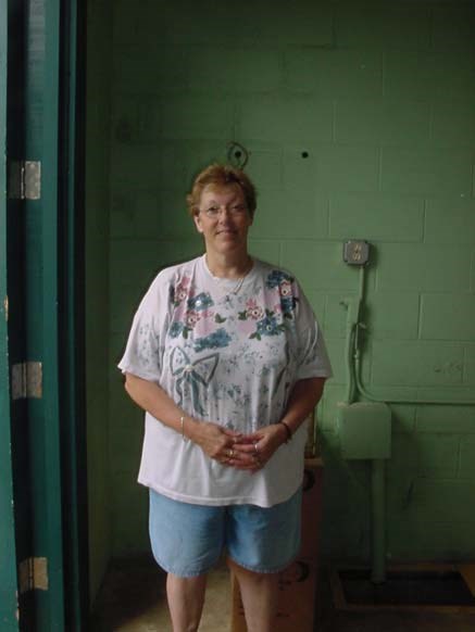 a woman in a tee shirt stands in front of a green wall