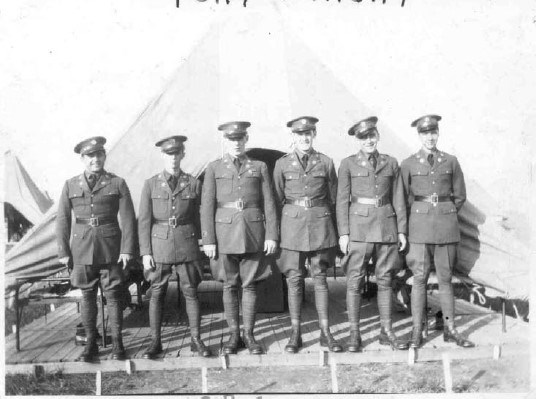 six men in military uniforms stand in front of a tent