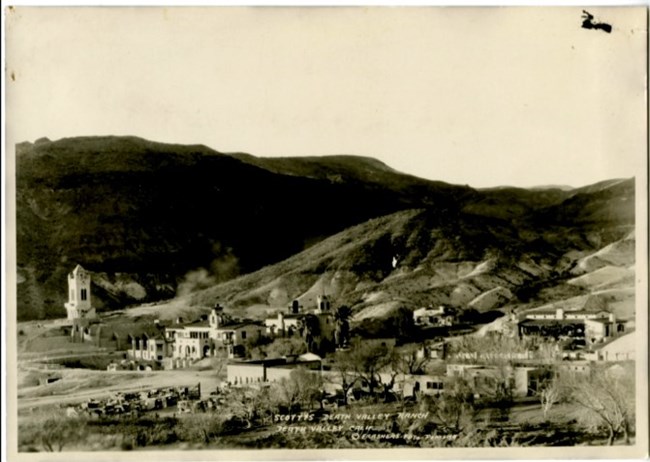 Buildings within Scotty's Castle National Historic District in foreground, mountains in background.