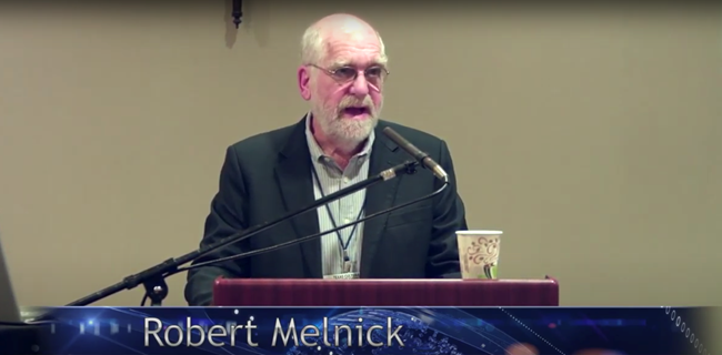 Robert Melnick: A non-audio described version of the presentation on YouTube Robert Melnick speaking at lectern. This image links to a non-audio described YouTube presentation.