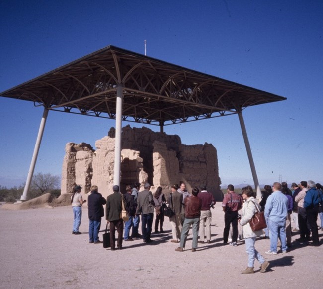 lt= People outside a historic ruin with a modern roof covering