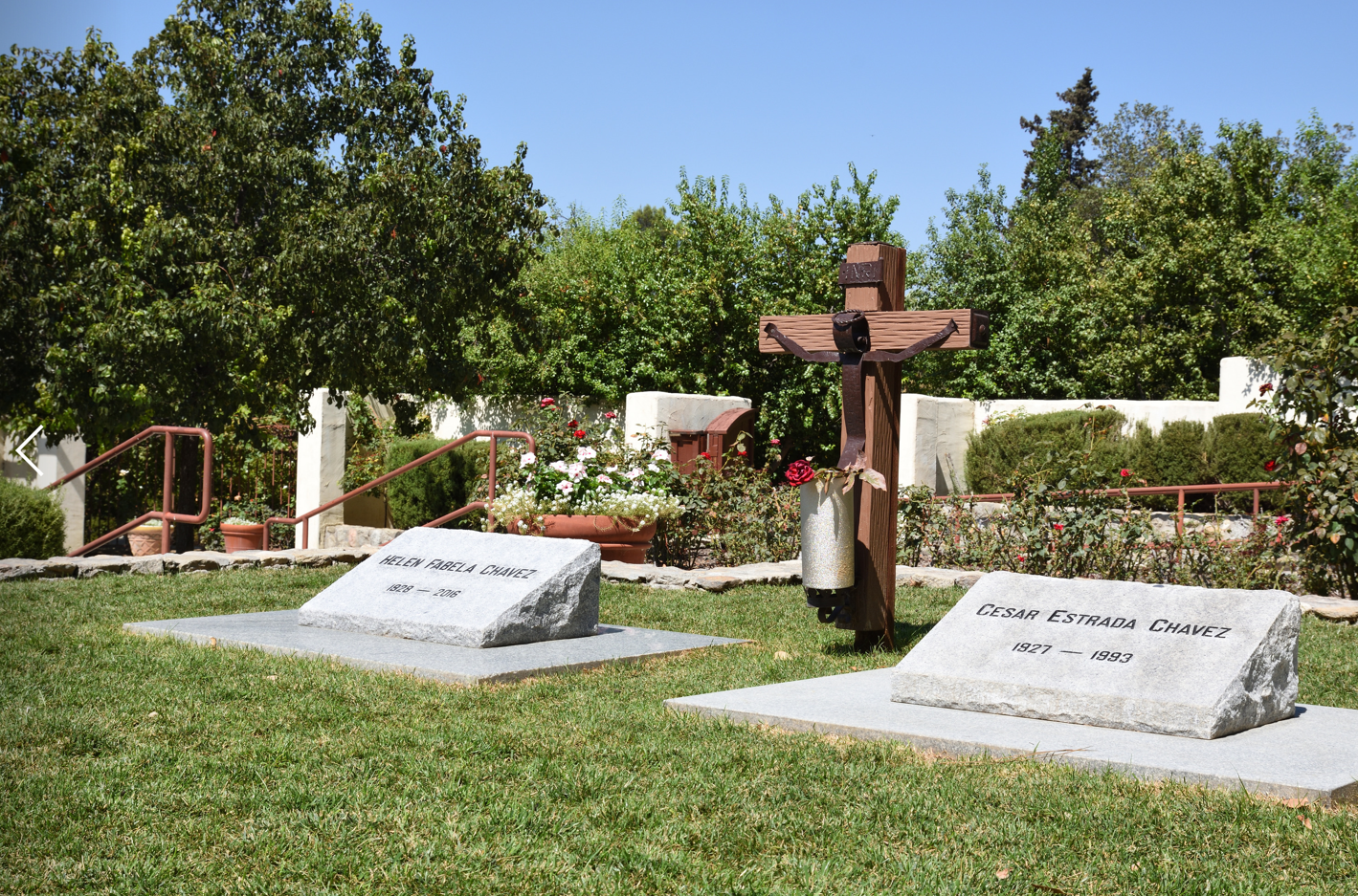 Between two graves is a rustic wooden cross with a human figure attached in iron.