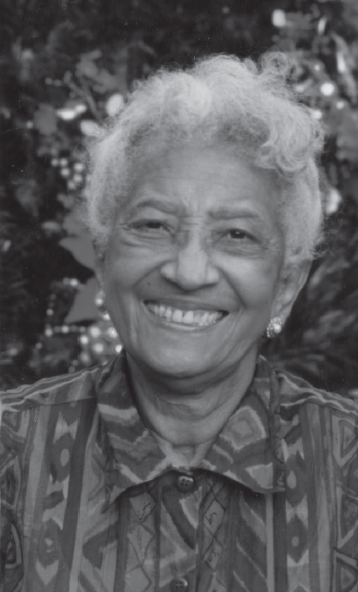 a Black woman with grey hair and a patterned collared shirt smiles.