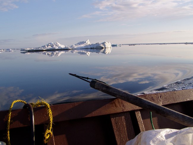 From a hunting boat, we see the tip of a seal harpoon resting on the wall of the boat.