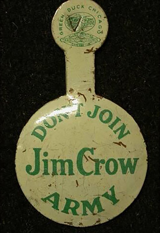 A white metal collar clip printed in green. The collar clip has a larger, circular end printed “Don’t Join Jim Crow Army.” A smaller circular end is connected by a length of metal designed to fold over a collar.