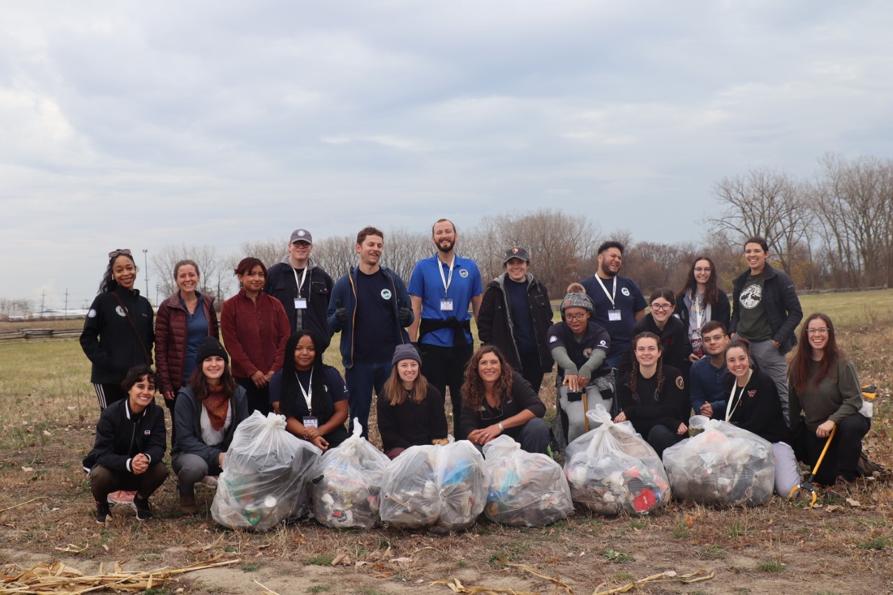 A group of Community Volunteer Ambassadors and Conservation Legacy staff pose with full garbage bags from a volunteer service project.