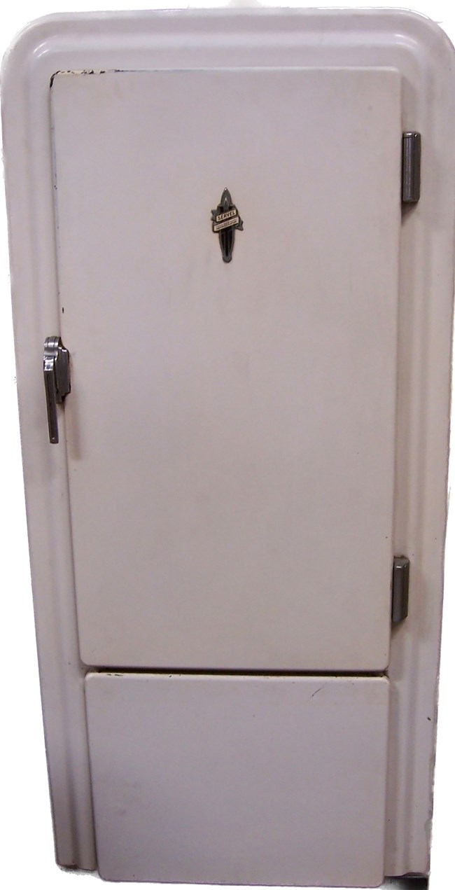 A white fridge with chrome handle on the left, hinges on the right, and a Servel logo. The drawer is on the bottom; the door on top.