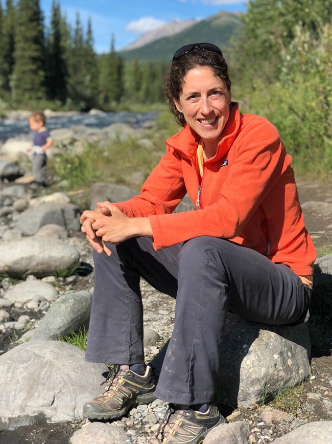 A woman sitting by a river.