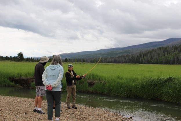 An individual showing two other individuals how to fish