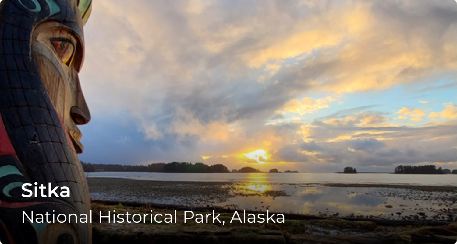 A totem pole and sunset over water. In the lower left reads, Sitka.
