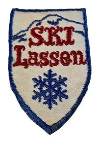 A photo of an embroidered patch in the shape of a chevron with the words "SKI Lassen" and a snowflake.
