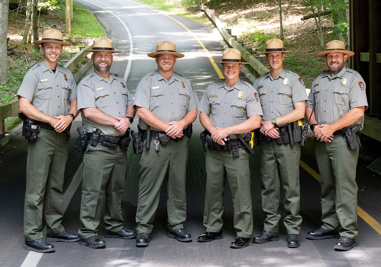 A group of uniformed people in straw flat-brimmed hats, standing in a line.