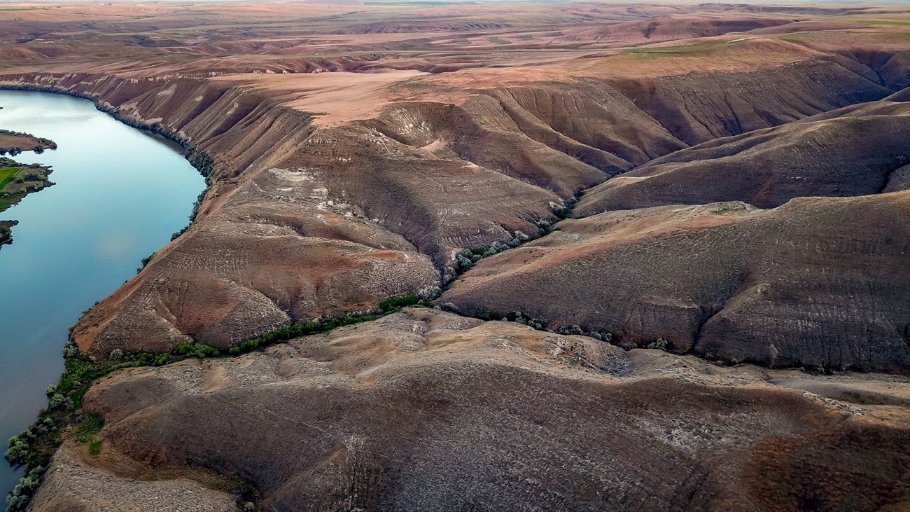 A turquoise blue Snake River flows through the brown hills at Hagerman Fossil Beds National Monument.