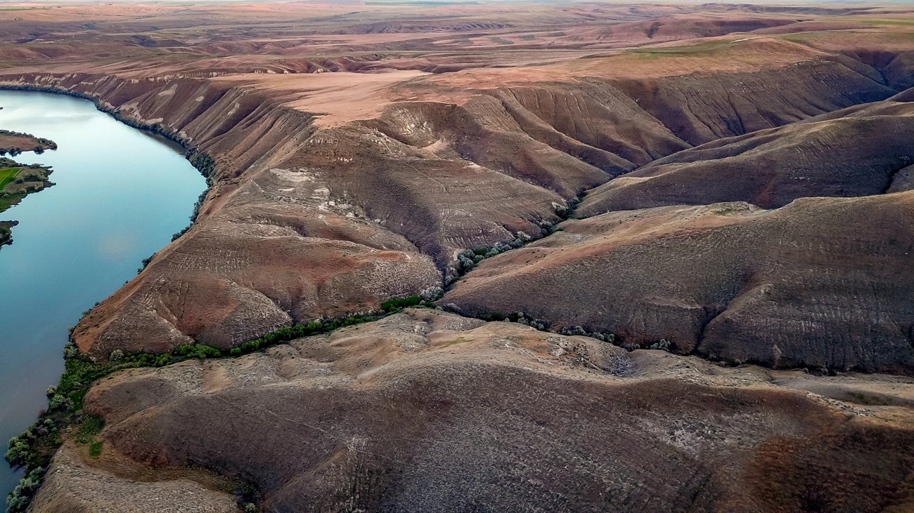 Snake River flowing through Hagerman Fossil Beds National Monument A turquoise blue Snake River flows through the brown hills at Hagerman Fossil Beds National Monument.
