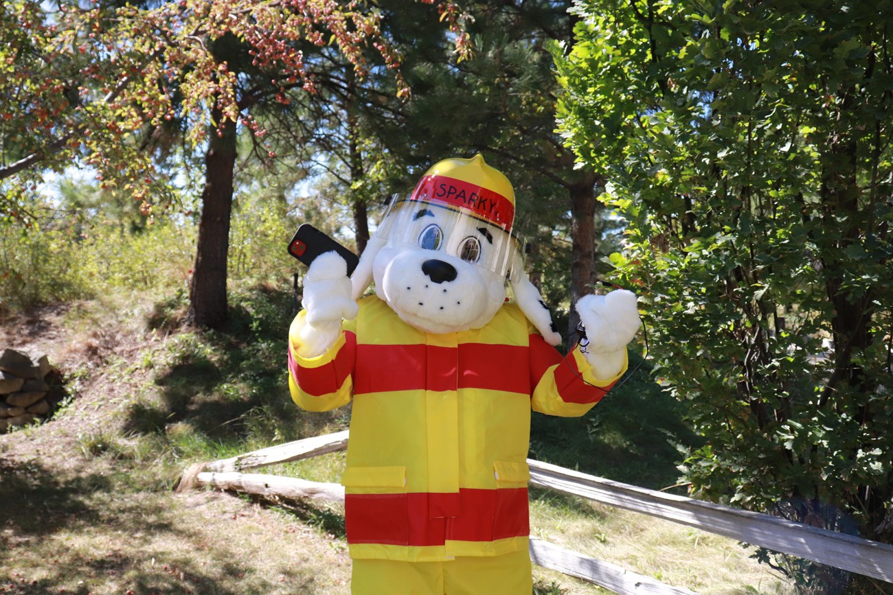 the "Sparky the Fire Dog" mascot holding up a phone and charger