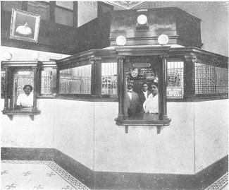 A center bank counter window with three employees behind the counter and bars and and second counter window with a fourth employee on the left