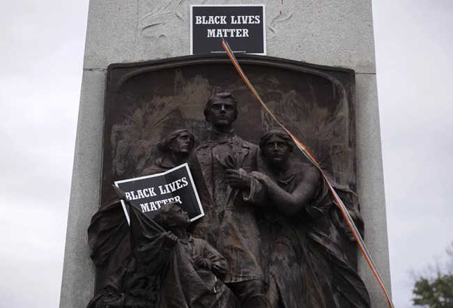Statue celebrating the Confederacy with its subjects holding "Black Lives Matter" signs.