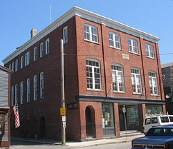 A three story brick building with rows of tall windows.