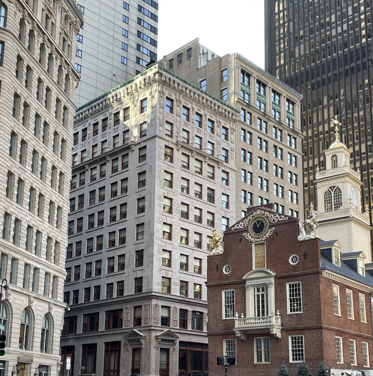 A 15 story building on a street corner across the street from a historic brick building.