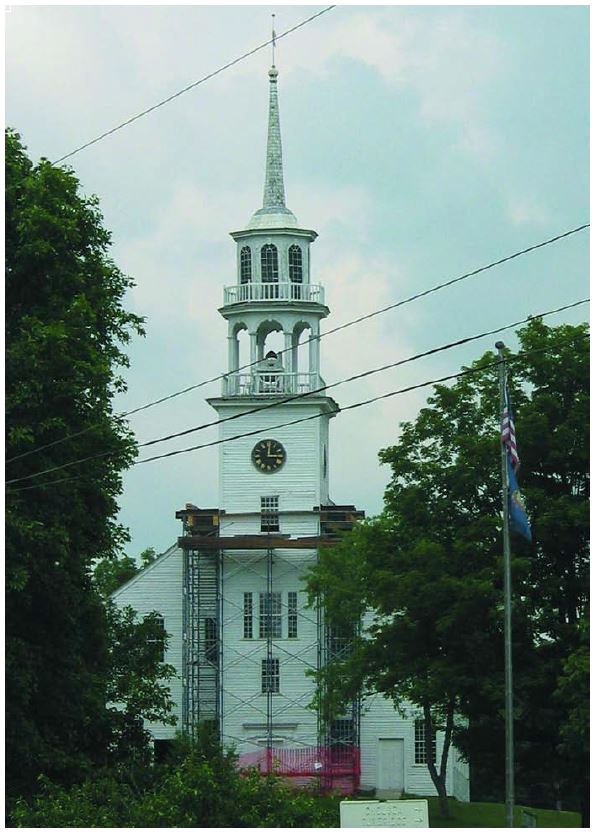 Scaffolding surrounds the half of the support tower of a steeple with clock, belfry, lantern, and spire.