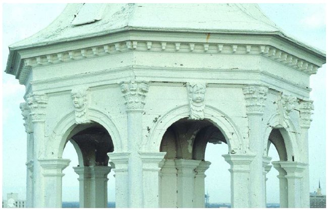 Cherub face centered above arches on the forming an ornate lantern of a steeple.