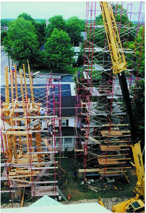 On the left tall scaffolding surrounds timber framing and a crane stands in front of a damaged church steeple surrounded by scaffolding.