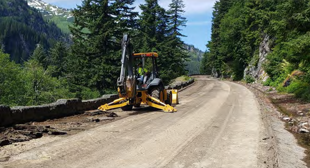 A yellow construction vehicle sits upon a dirt road