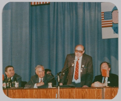 And old photograph of Jim Stimpfle speaking behind a table on a stage in Provideniya, Russia.