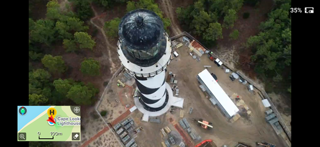 Drone view of the construction site of Cape Lookout Lighthouse. A fence is around the lighthouse, a trailer is to the right, and trees have been cleared.
