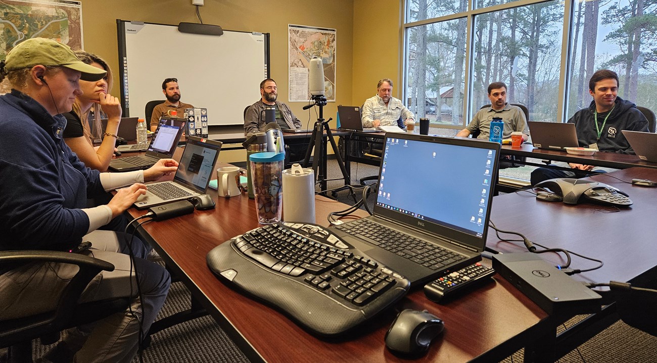 People sitting around a conference table with laptops in front of them