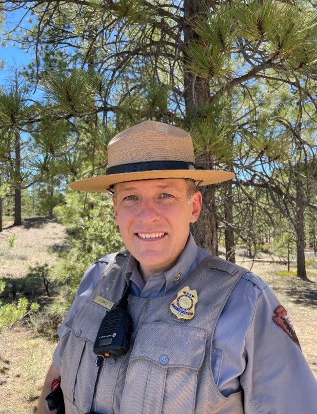 A tan-uniformed person with a flat-brimmed straw hat and short hair.