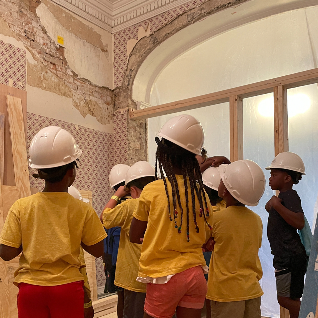 A group of students look up at a wall in a historic home in need of restoration.