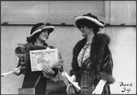 two women standing next to each other, one holding a copy of the woman's journal and suffrage news.