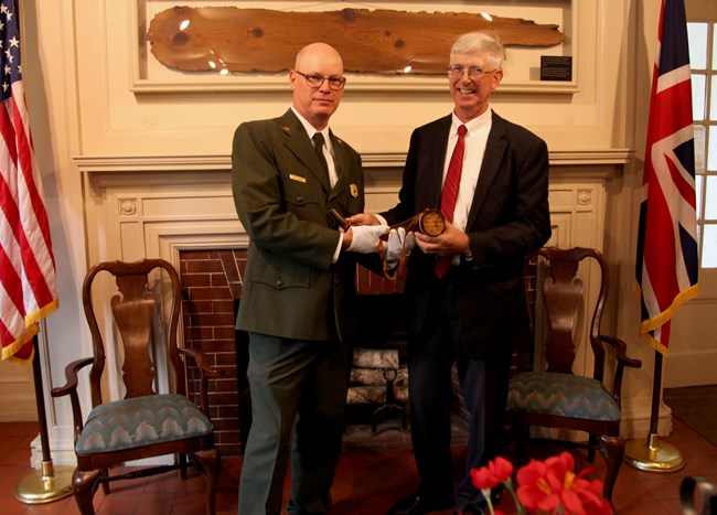 Former Superintendent BJ Dunn and Marshall Buttrick A National Park Service Ranger and a man in a suit holding a powder horn
