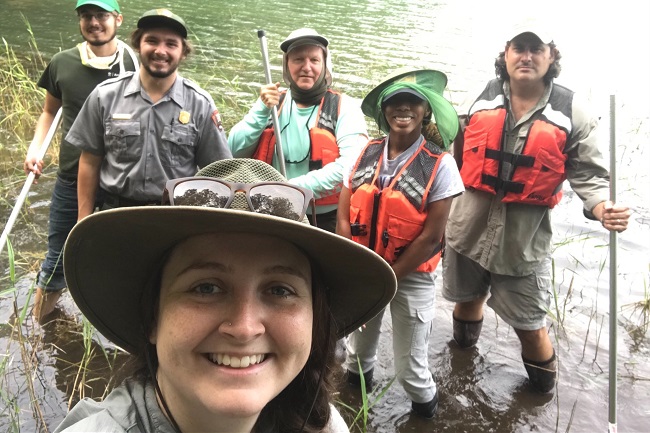 Science crew standing in shallow water taking a selfie