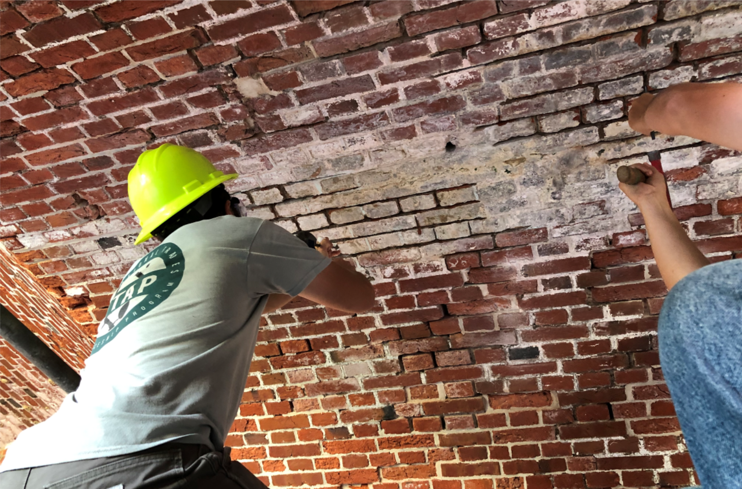 Reach for the ceiling Young men repairing masonry joints