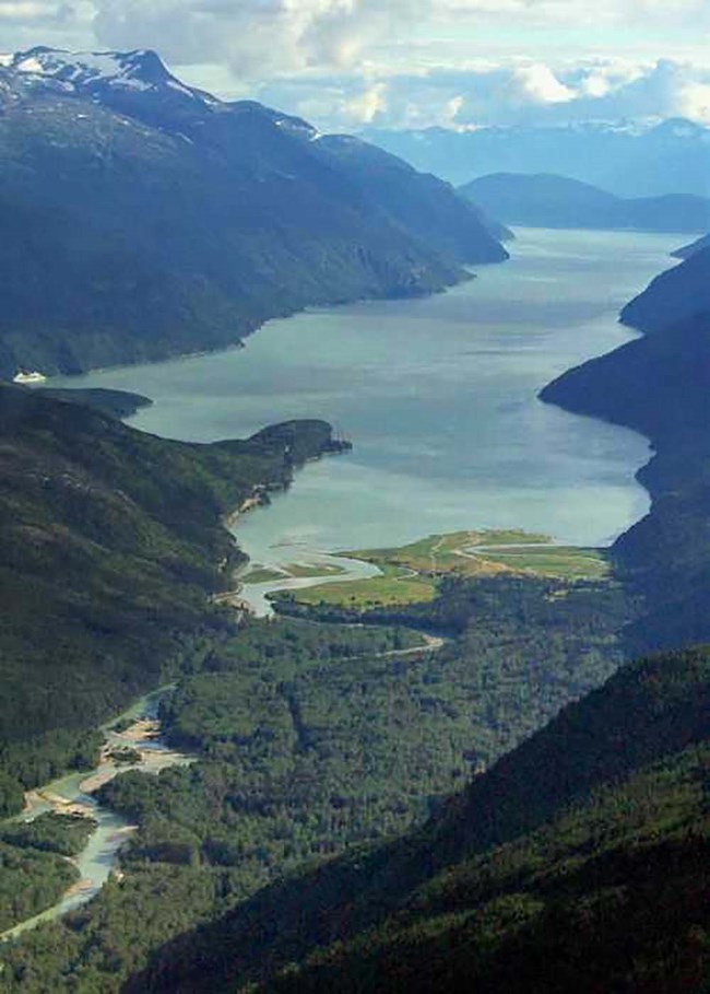 Taiya River_web An aerial view of a forested river valley with a river flowing into a fjord