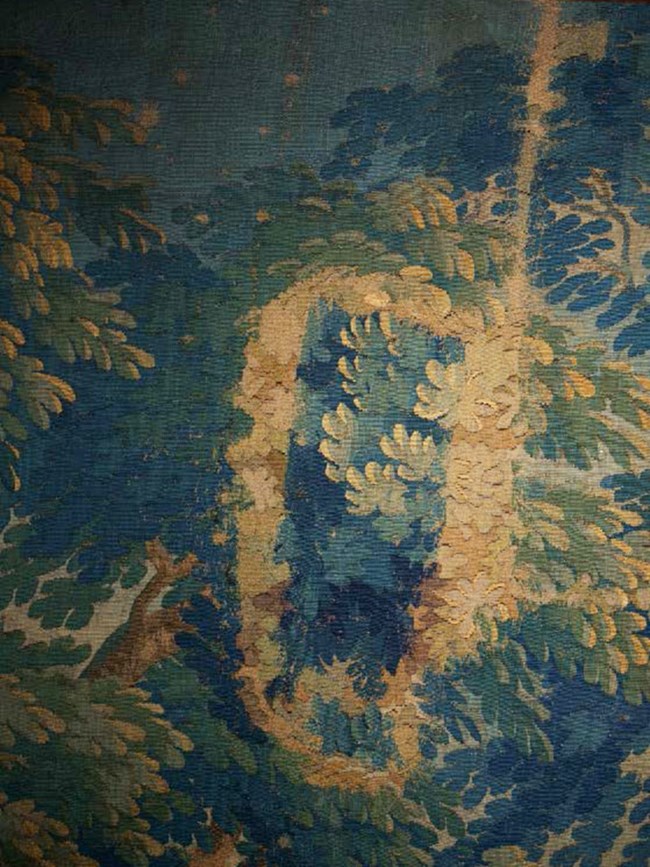 Detail of a tapestry showing large areas where color has faded to brown.