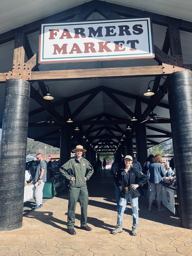 lt= Tatum poses with a National Park Service Ranger at a farmers' market.