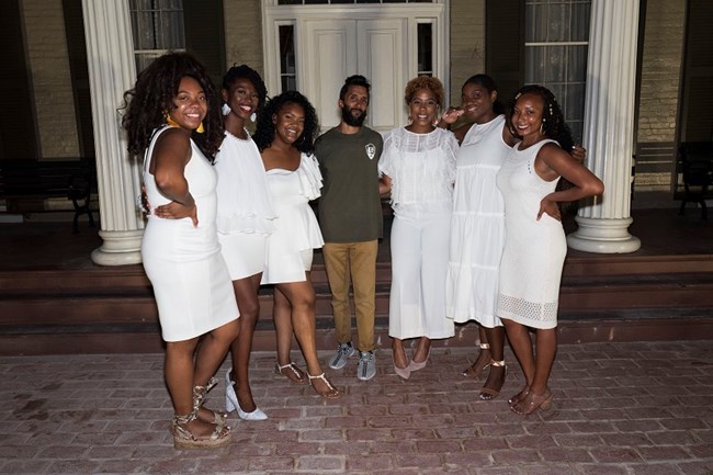 Twenty and Odd crew six women dressed in white posing and smiling at the camera with one man in the middle